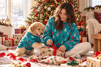 Woman and Golden Retriever puppy in matching sweatshirts opening gifts on Christmas morning