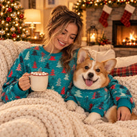 Woman with hot cocoa and a Corgi in matching sweatshirts on the sofa